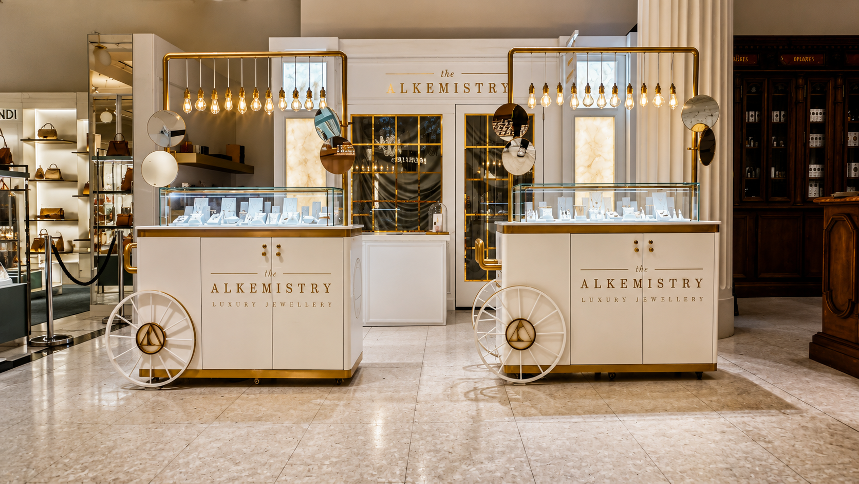 The Alkemistry luxury jewellery pop-up at Selfridges London featuring bespoke white and gold display carts, illuminated pendant lighting, glass showcases and a premium retail environment designed and delivered by NORTHBANKS.